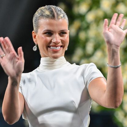 a white woman in a white dress waving to a crowd
