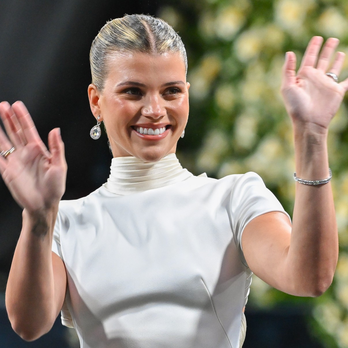 a white woman in a white dress waving to a crowd