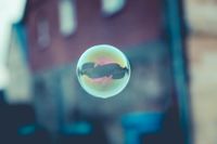 A soap bubble floats against a blurred background