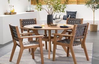 A wooden outdoor dining table and chairs on a paved patio