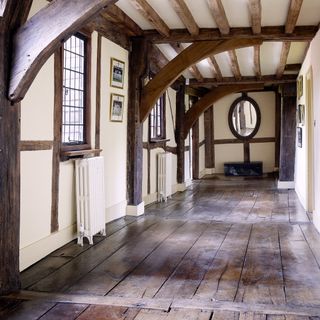 Original suspended wood floor in a period property, with beige walls, windows and wood beams on the walls and ceiling