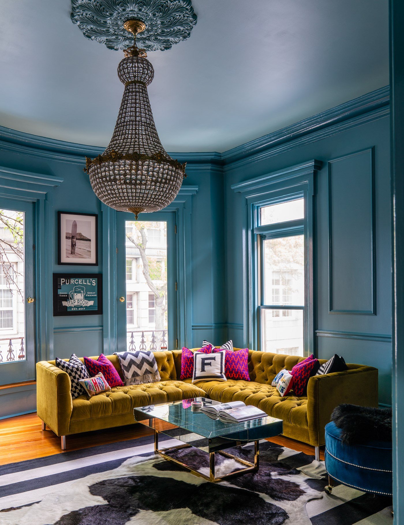 Blue living room with yellow sofa and pink cushions