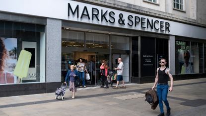 Pedestrians walking by an M&S store front in Swansea city center.