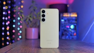 Samsung Galaxy S26 FE against a colorful, softly blurred studio background.