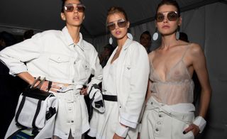 Models wear white jackets and top, and see through top