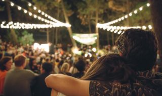 outdoor date ideas - Young couple embracing at night music festival