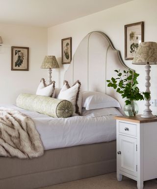 Neutral bedroom with cream walls, large headboard and pillows