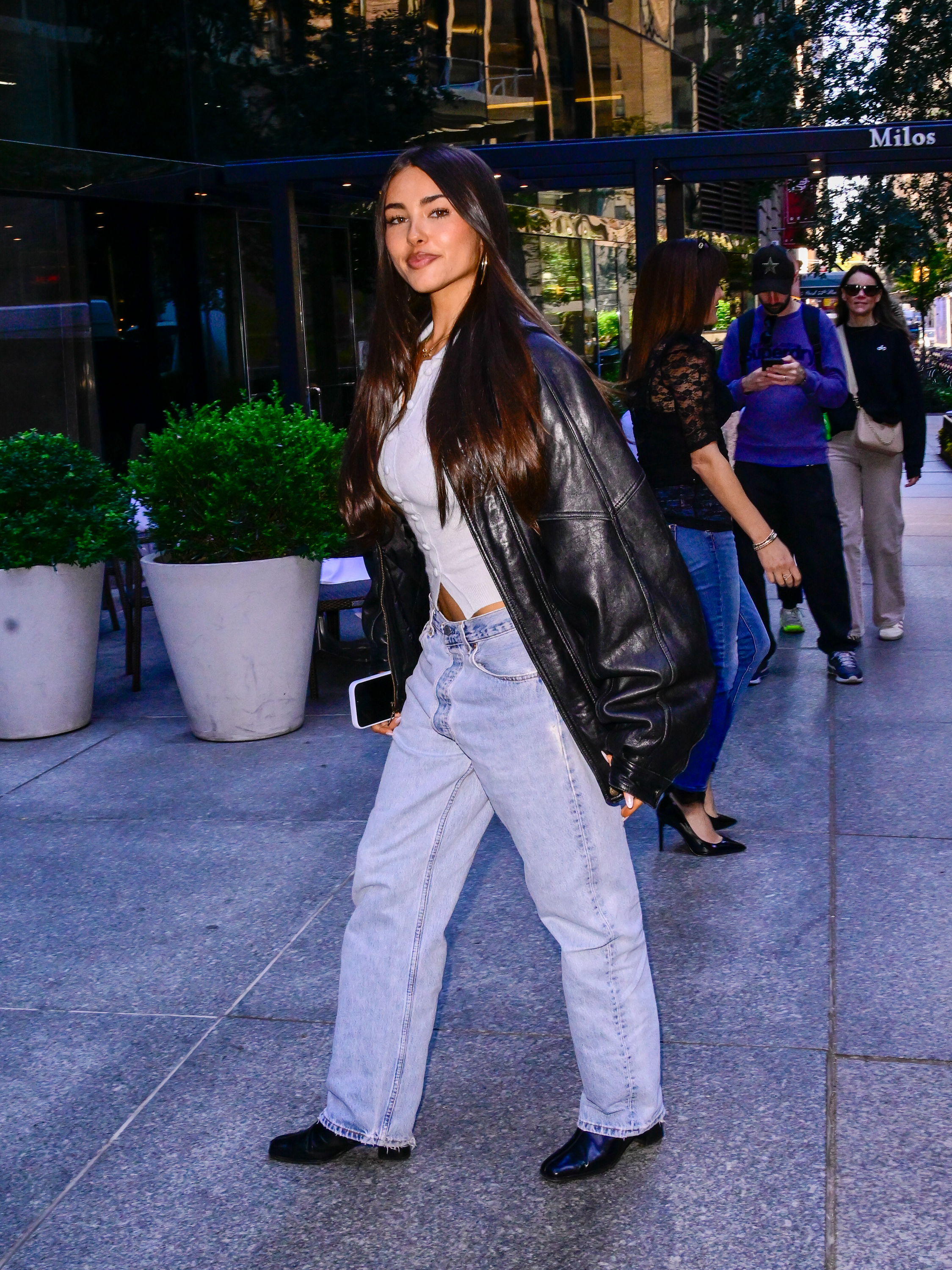 Madison Beer wears an oversize leather bomber jacket with jeans and boots.