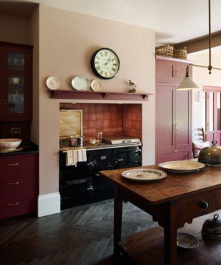 Small modern farmhouse kitchen painted in pink hues and a traditional AGA range cooker in the centre of the kitchen