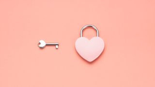pink heart shaped lock with key on pink background
