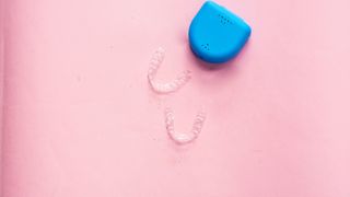 clear aligners and blue case on pink background