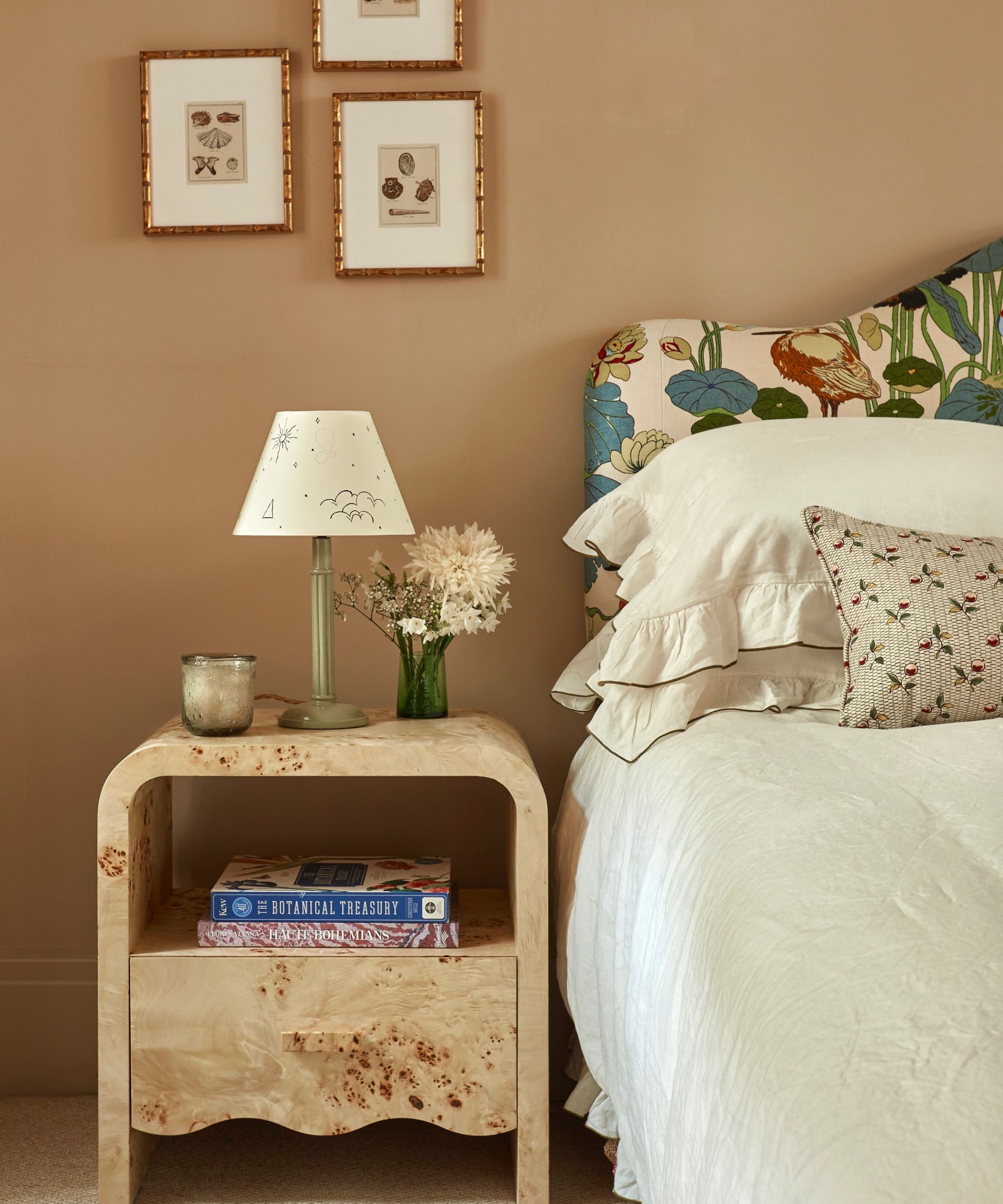 beige bedroom with bold patterned upholstered headboard and neutral bedding with a burl wood nightstand