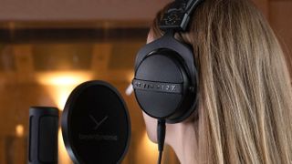 Beyerdynamic DT 770 Pro X Limited Edition worn by a woman, facing away from the camera, singing into a studio microphone