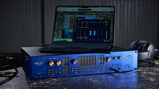 A Focusrite ISA C8X audio interface on a worn wooden desk with a laptop on top of it.