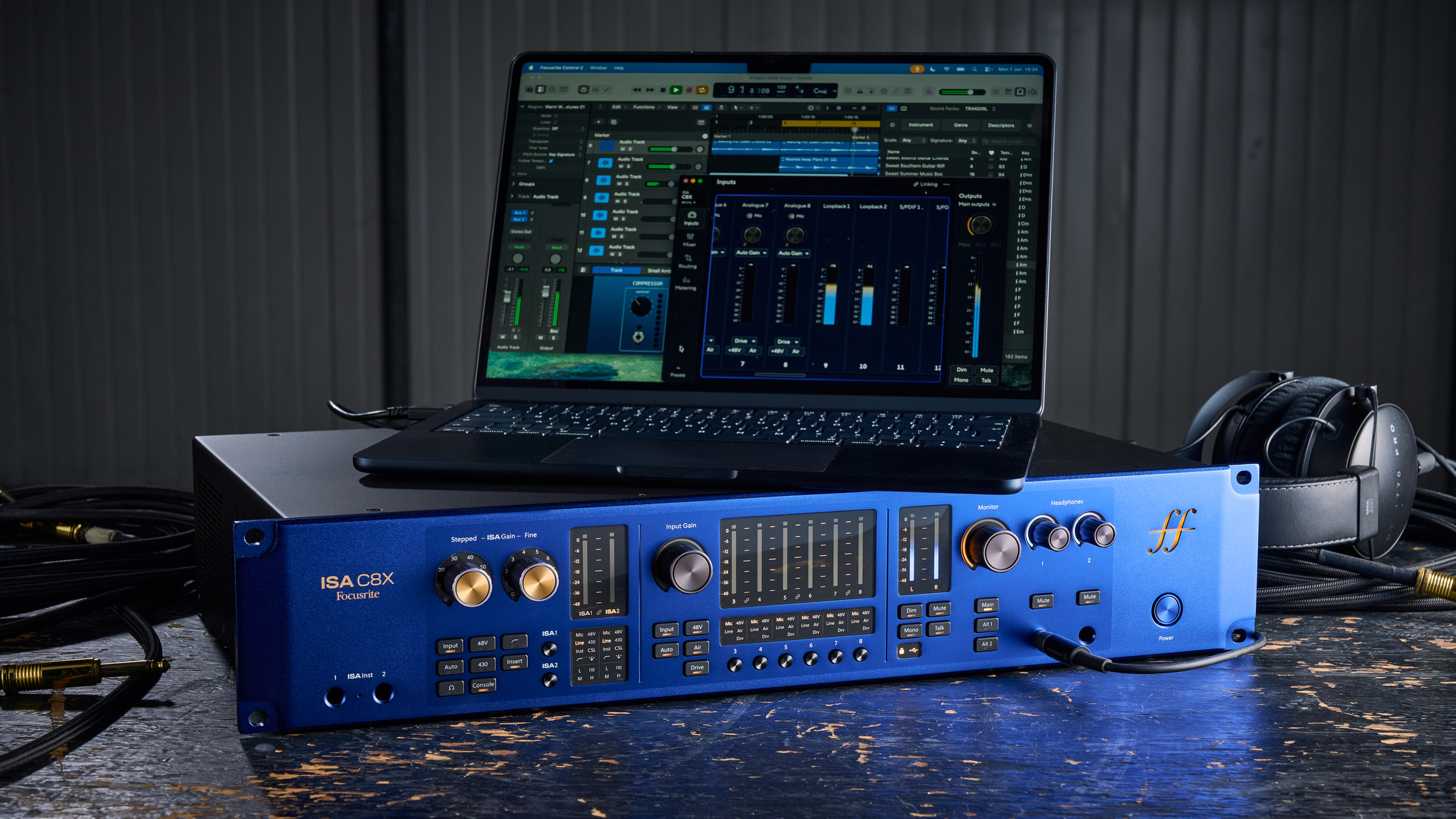 A Focusrite ISA C8X audio interface on a worn wooden desk with a laptop on top of it.