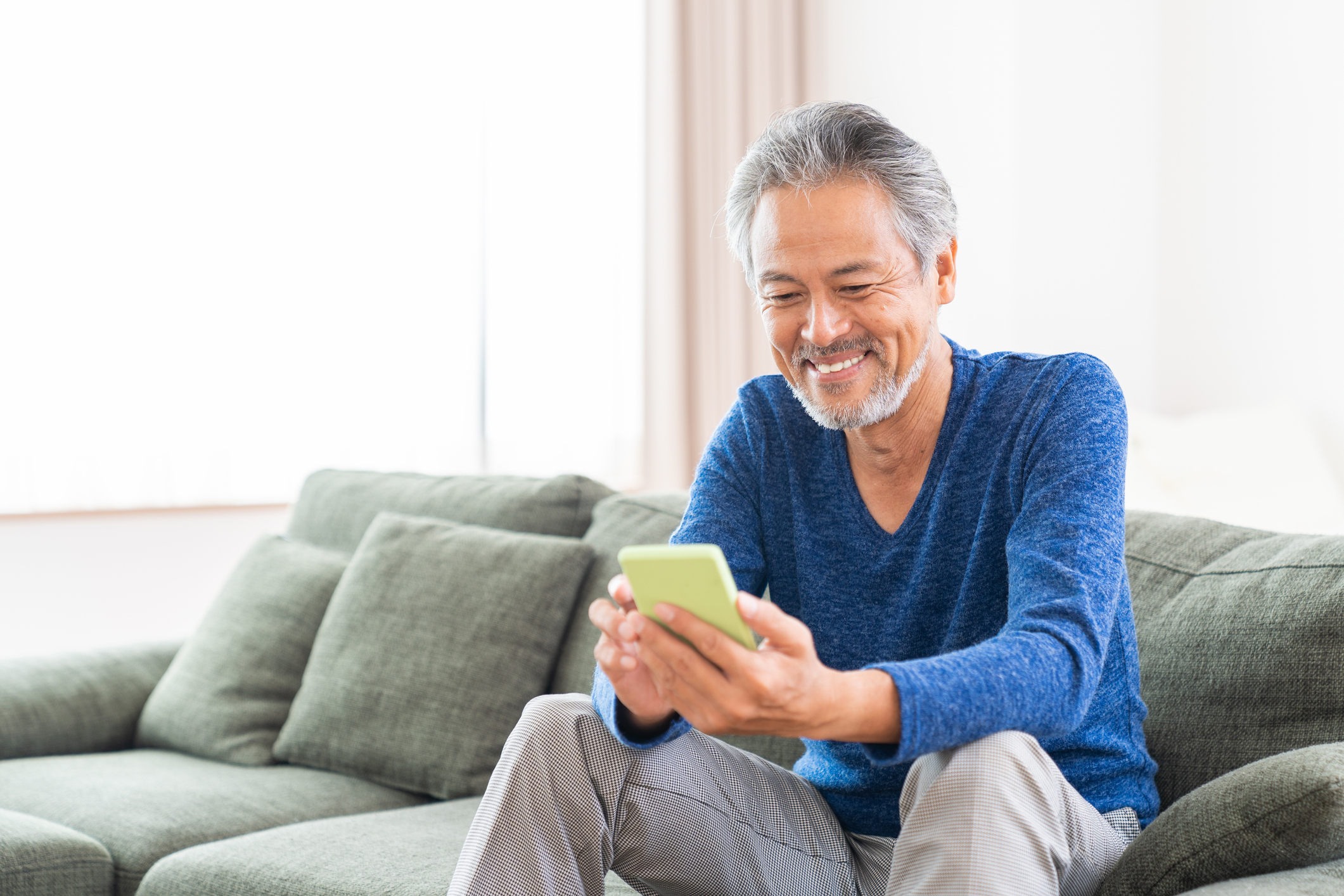 A man is scrolling through his cell phone smiling.