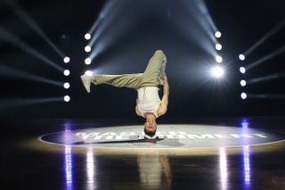 Canon EOS R5 Mark II sample image: a breakdancer dancing on a wooden floor, backlit with laser lighting