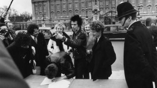 The Sex Pistols with their manager Malcolm McLaren signing a new contract with A&M Records, after being dropped from EMI, outside Buckingham Palace, London. The contract was terminated in one week.