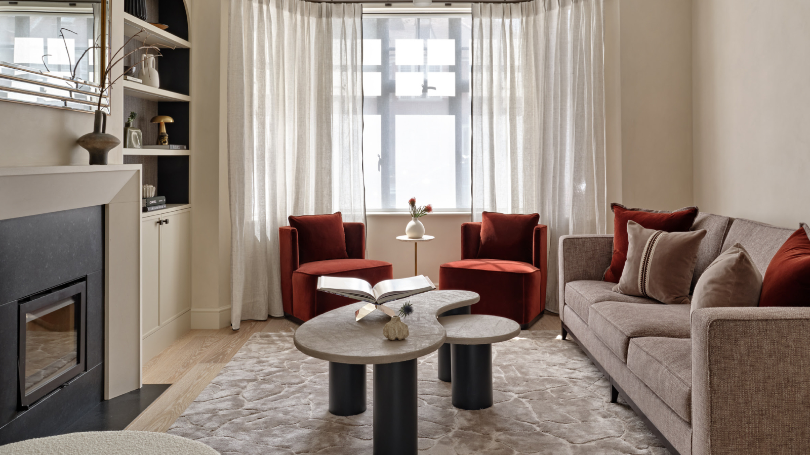 living room with fireplace, large bay window, sofas, coffee table and built in storage in alcove