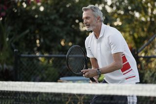 Sam Neill as Stan playing tennis.