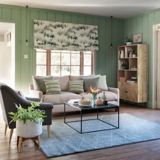 Green living room with wall panelling, wood flooring and a grey rug