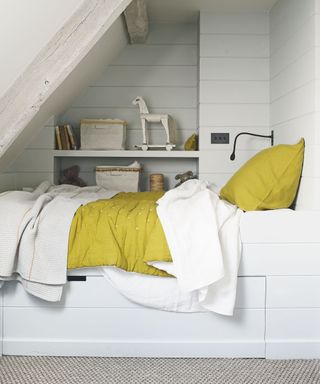 An example of guest bedroom ideas showing a white bed built into an alcove next to shelving