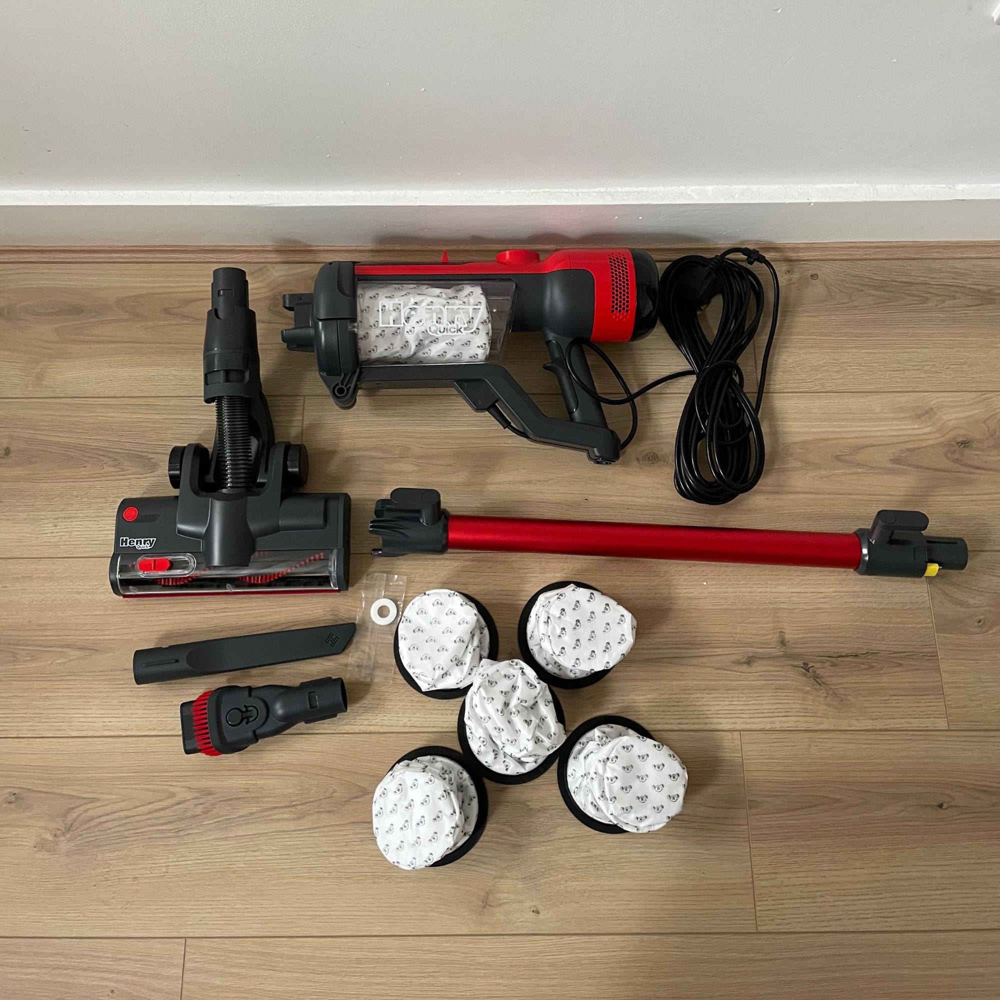 Components of the Henry Quick Corded  Vacuum Cleaner laid out on wood-effect flooring