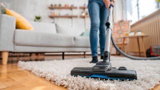 woman vacuuming rug in living room