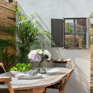 Courtyard with mirror on white wall in front of garden dining set