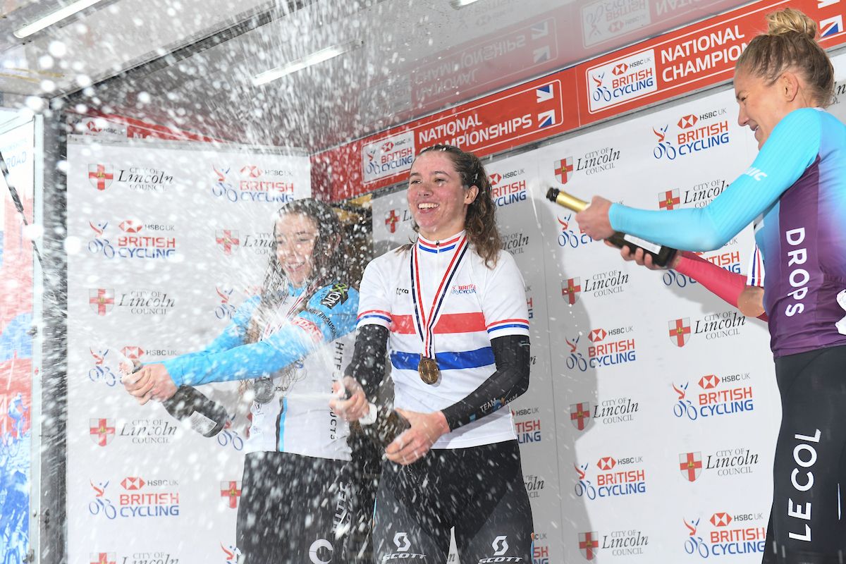 Picture by Simon Wilkinson/SWpix.com - 17/10/2021 - Cycling - Women's National Road Championships - Rapha Lincoln GP - Lincoln, England - Podium - Winner DSM's Pfeiffer Georgi sprays champagne with Team Coop-Hi Tec Products Josie Nelson in second place &amp; Drops-Le Col's Joss Lowden in third.