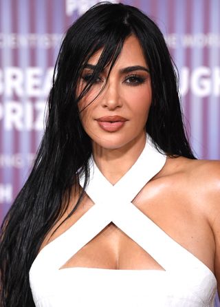 Kim Kardashian with a wet layered hair look and white dress.