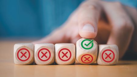 Hand flipping wooden block to change red cross mark to correct tick symbol