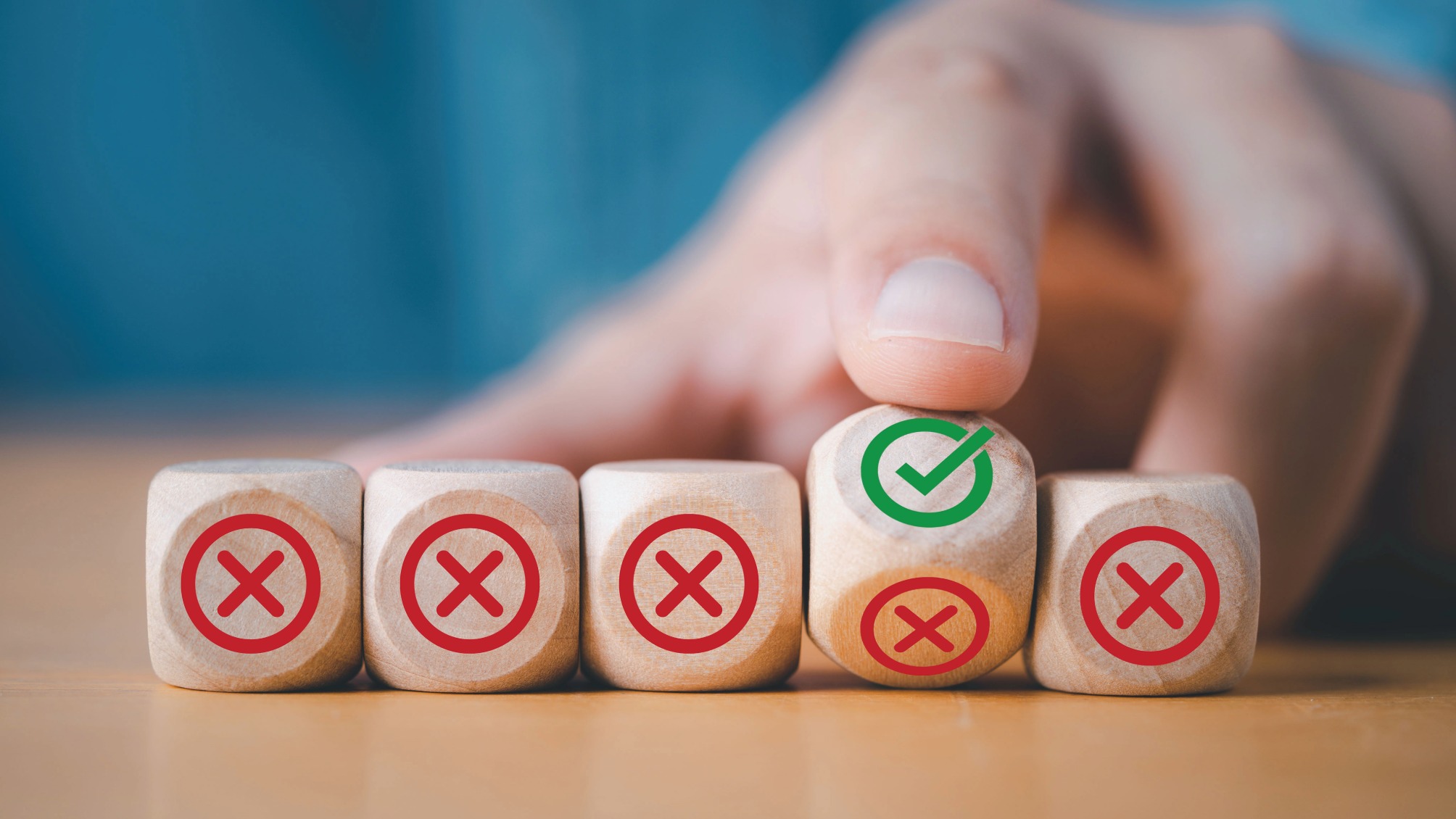 Hand flipping wooden block to change red cross mark to correct tick symbol