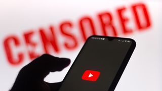  In this photo illustration the YouTube logo is displayed on a smartphone and a red alerting word "CENSORED" on the blurred background.