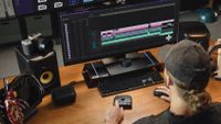 Editor using the TourBox Elite Creative Console while sat at a computer with a camera next to him