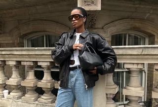 British fashion influencer @nlmarilyn wearing a leather bomber jacket with relaxed jeans and oversized sunglasses