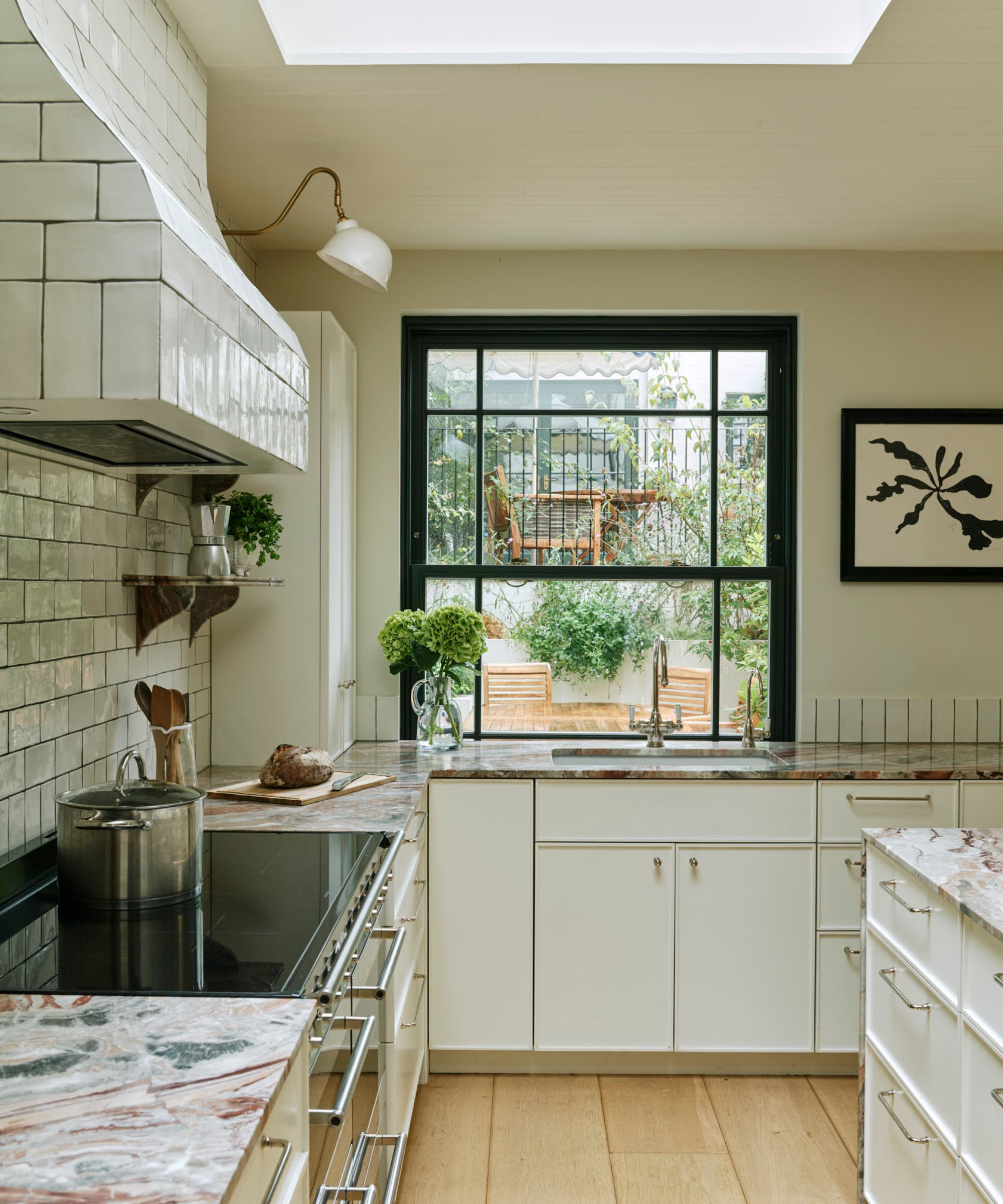 Neutral kitchen with white cabinets and beige walls, black window frames and statement marble countertops