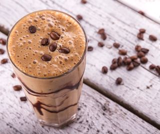A coffee smoothie with coffee beans scattered on top