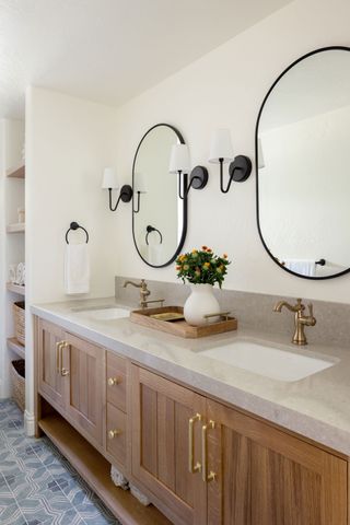 twin vanity unit with basins and brass faucets and twin mirrors above