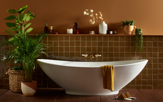 Dark bathroom idea with brown half tiles and brown painted wall and freestanding bath next to plants