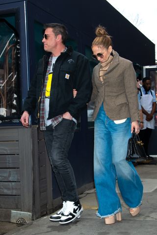 Jennifer Lopez styles wide leg puddle jeans with platform heels.