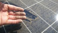 Hand rubbing dirt off a solar panel