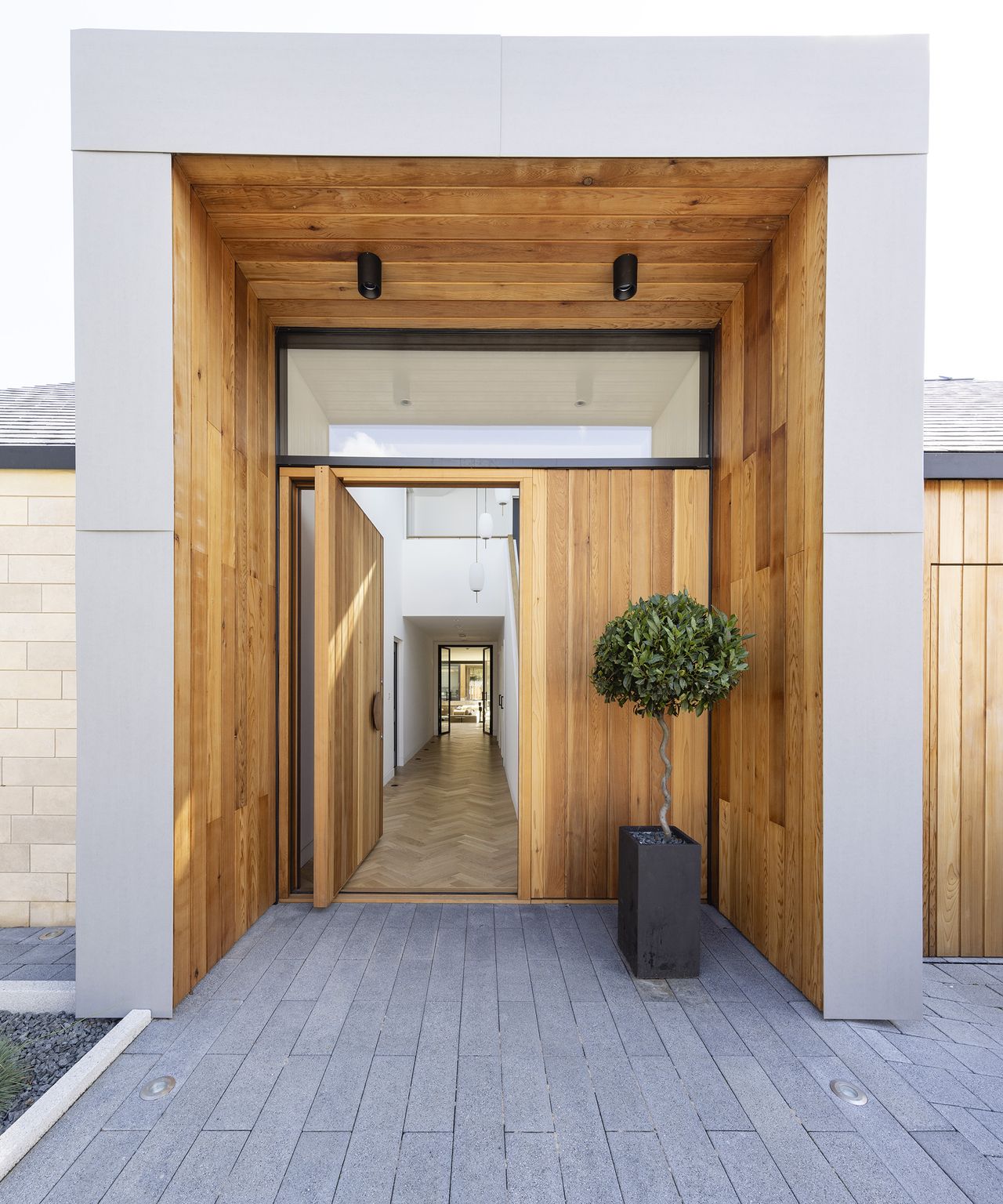 Contemporary front entranceway to a bungalow framed in timber with a potted bay tree