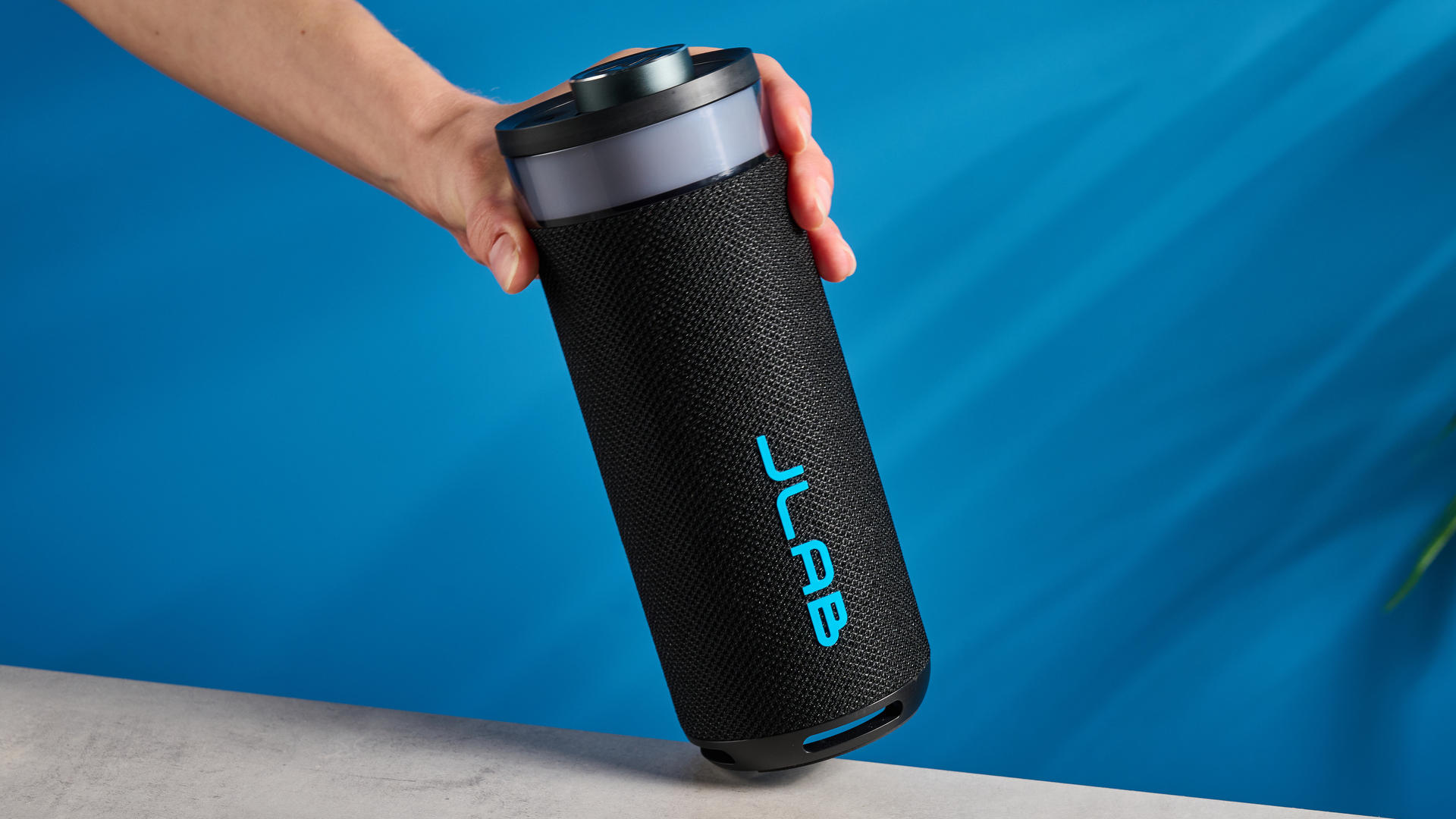 the jlab go party speaker in black with an LED RGB panel and jlab logo photographed in front of a blue background