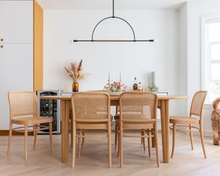 A white dining room with oak table and chairs