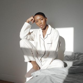 Marisa Martins sitting on a bed wearing white pajamas