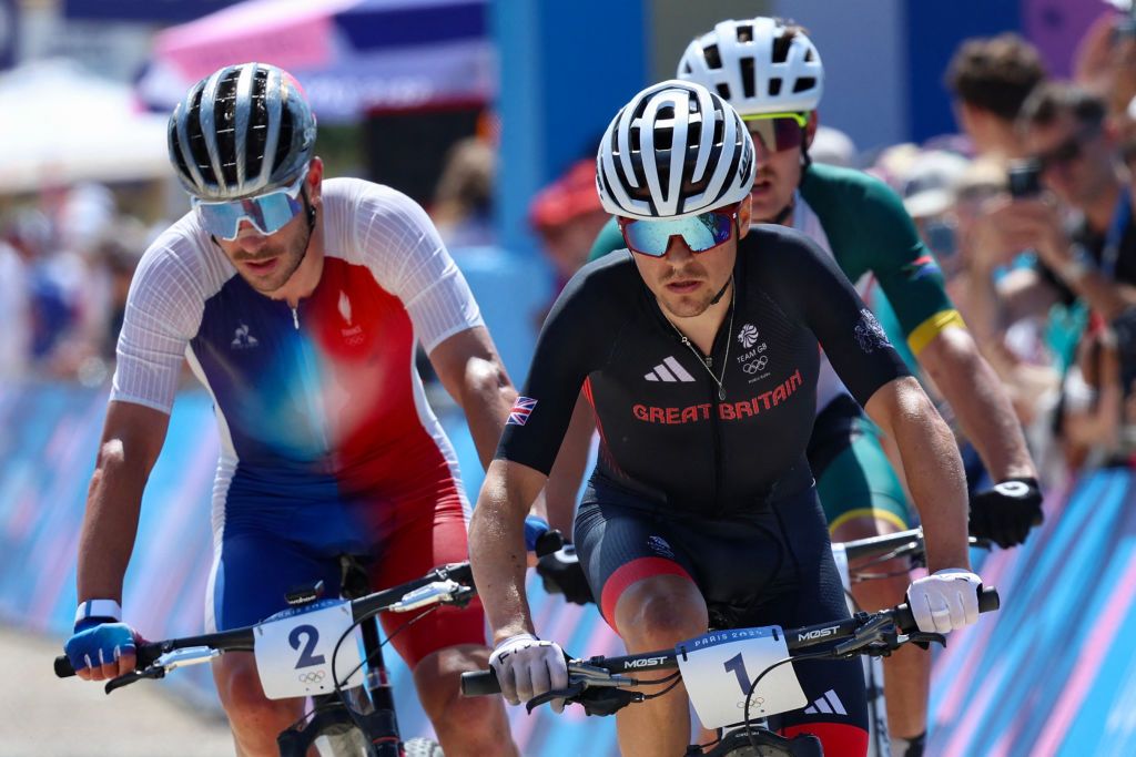 Britain's Thomas Pidcock cycles ahead of France's Victor Koretzky (L) and South Africa's Alan Hatherly (R) as they compete in the men's cross-country mountain biking event during the Paris 2024 Olympic Games in Elancourt Hill venue in Elancourt, on July 29, 2024. (Photo by Emmanuel DUNAND / AFP)