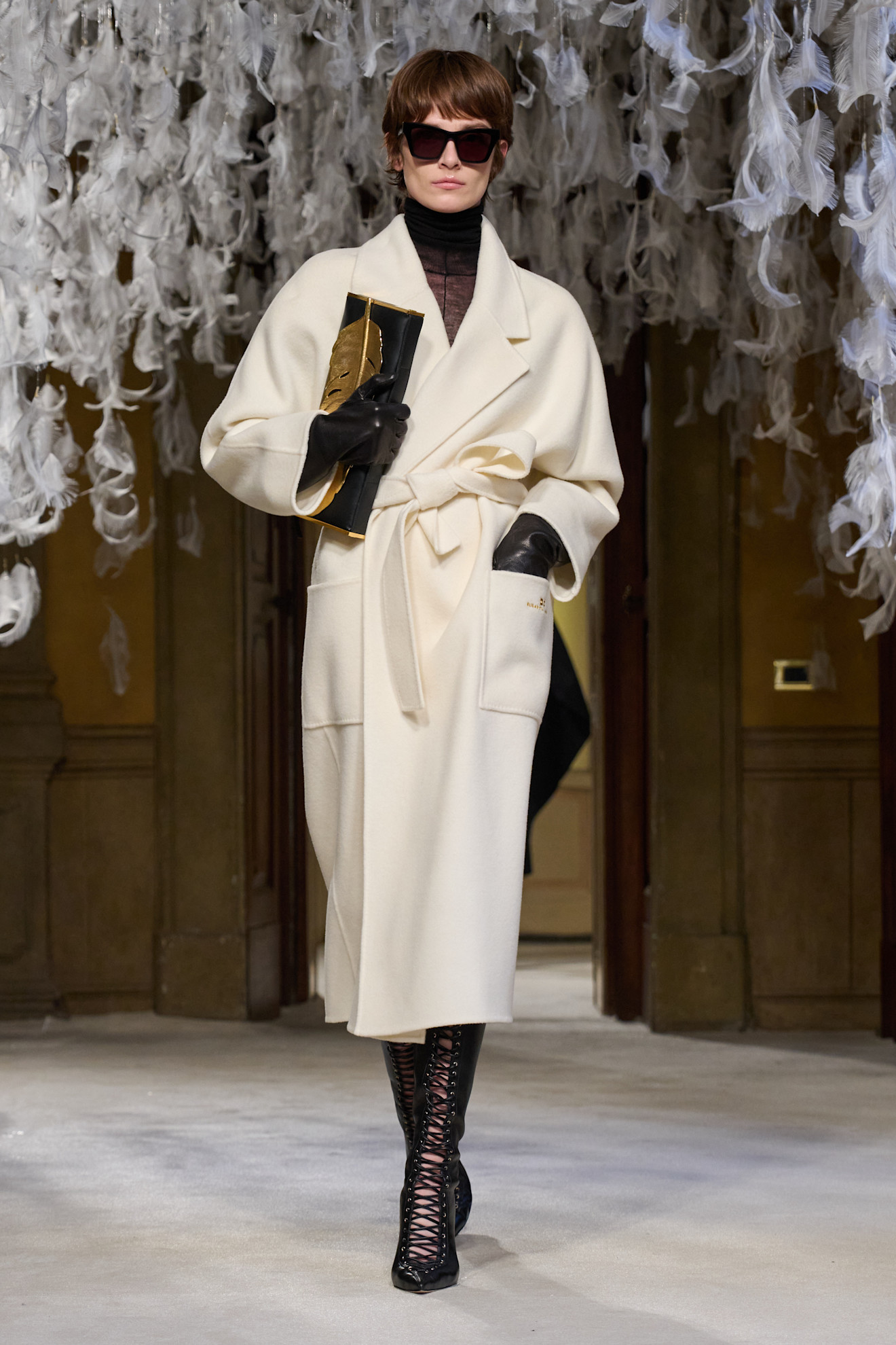 Model wears lace-up knee-high boots on the A/W26 runway