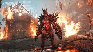 Character in metallic armor with spikes walking away from burning village in Lords of the Fallen