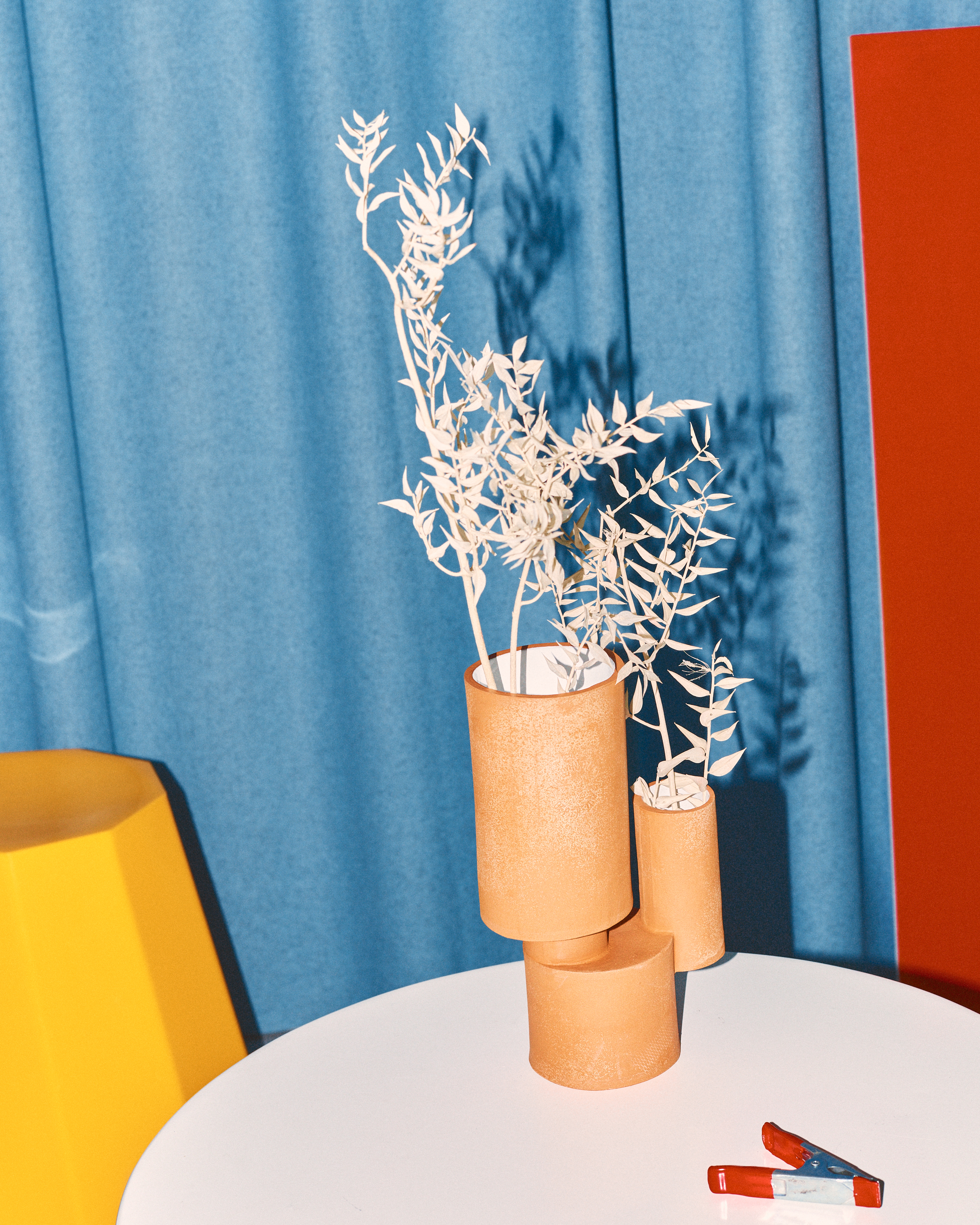 orange ceramic vase on table with dried flowers inside